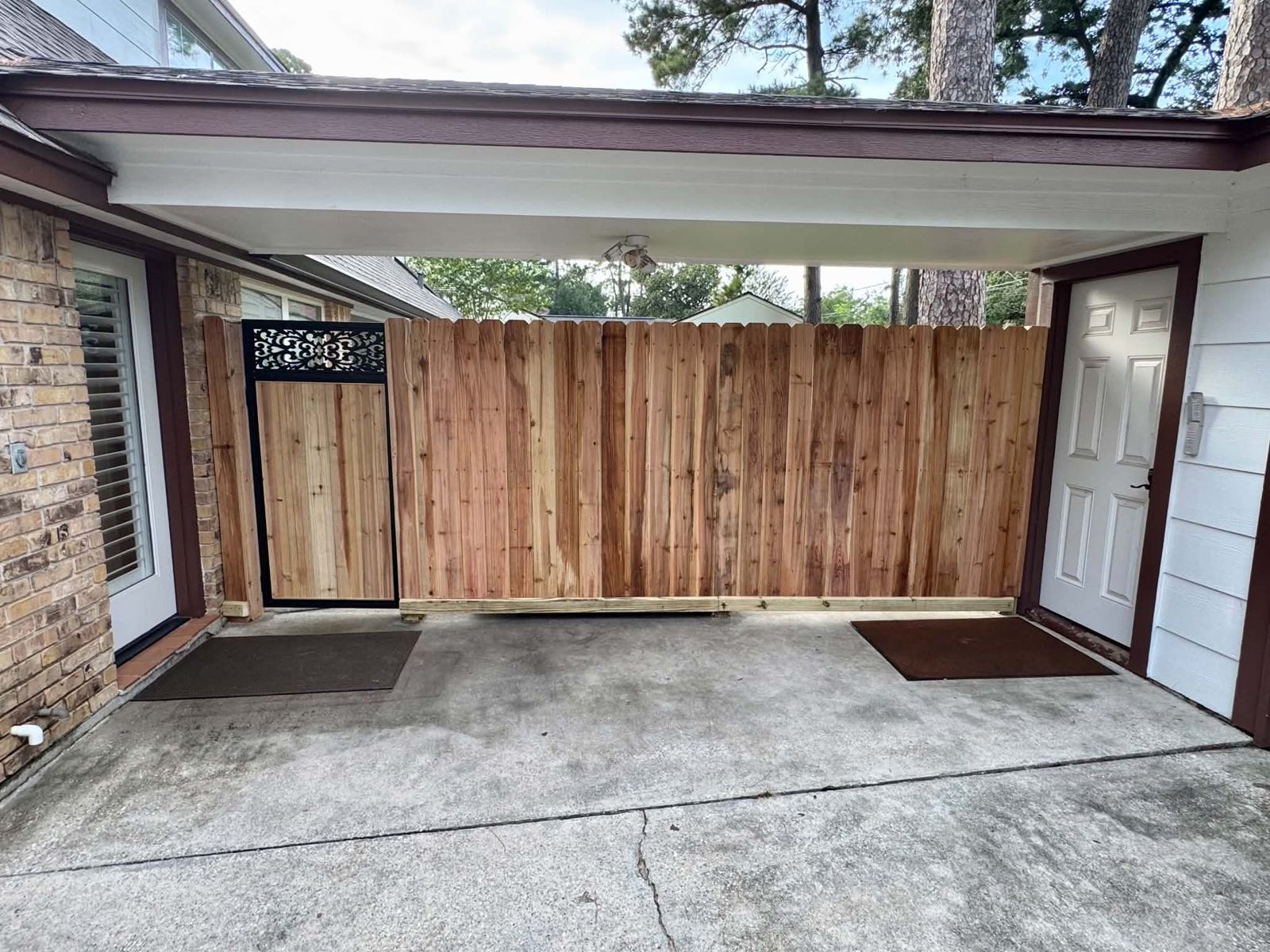 Wood fence with a decorative metal-top gate closing off a carport
